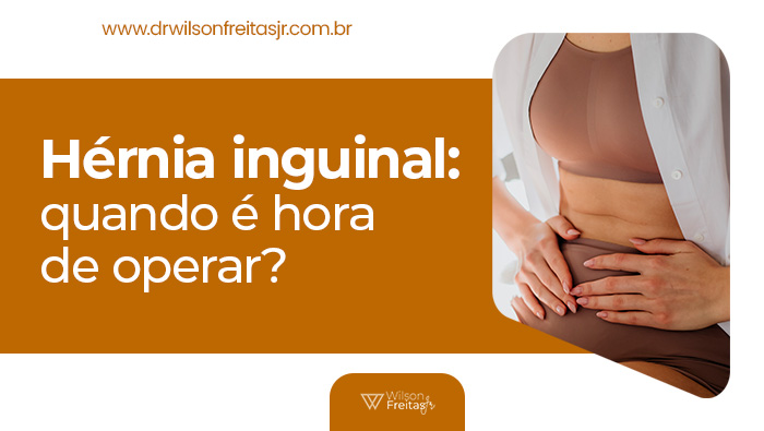 Mulher com as mãos sobre o abdômen inferior, aparentando desconforto ou dor, vestida com lingerie e camisa branca aberta.